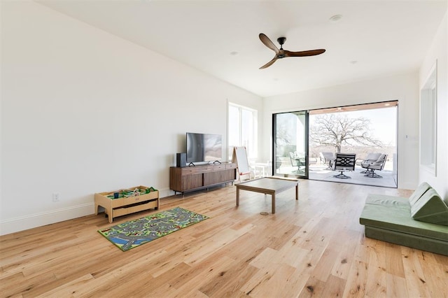 living room with ceiling fan, baseboards, and wood finished floors