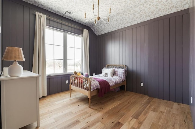 bedroom with a chandelier, lofted ceiling, visible vents, and light wood-style floors