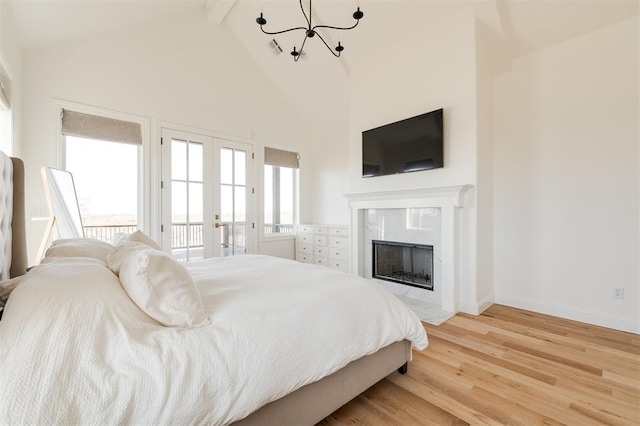 bedroom with light wood-type flooring, access to exterior, multiple windows, and a high end fireplace