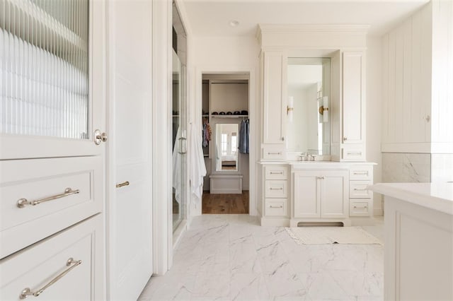 bathroom featuring marble finish floor, a spacious closet, and vanity