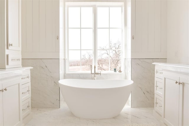 full bathroom with marble finish floor, a freestanding tub, and vanity