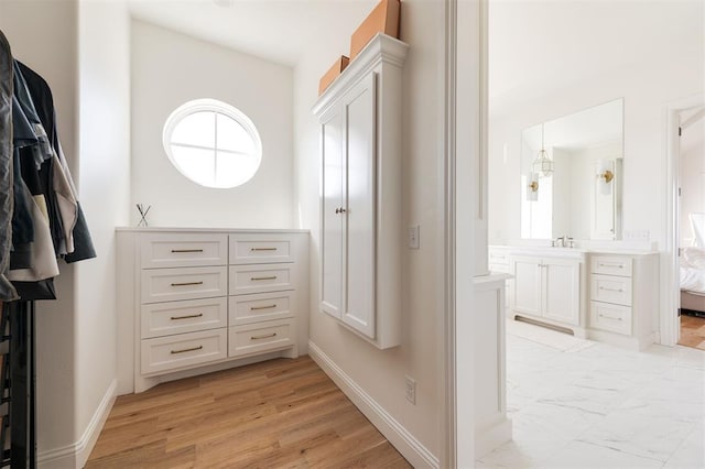 spacious closet with a sink and light wood-style flooring