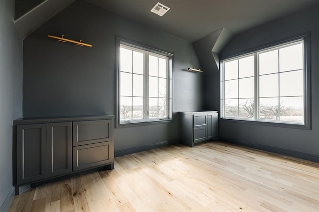 spare room featuring light wood-type flooring, a healthy amount of sunlight, visible vents, and baseboards