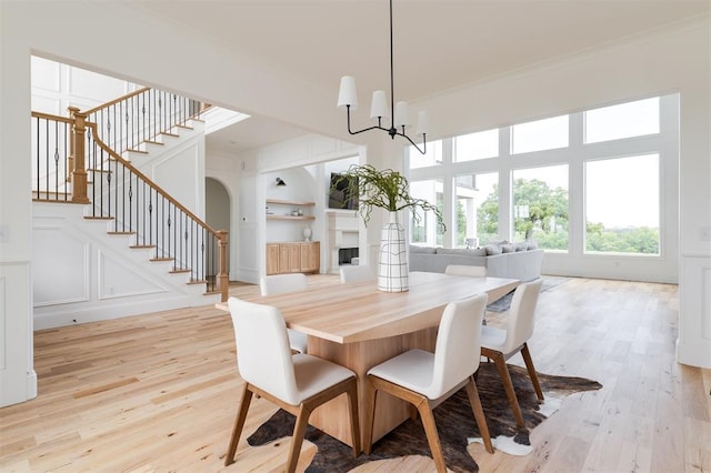 2909 High View Dr, Arcadia, OK 73007 - dining space with light wood-style flooring, stairs, crown molding, a chandelier, and a towering ceiling