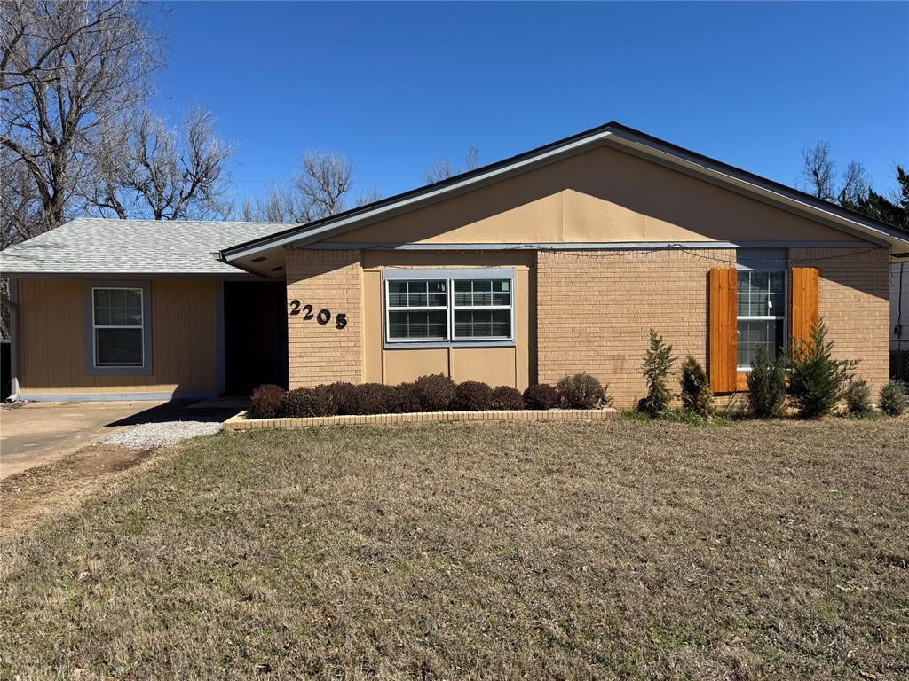 single story home featuring brick siding and a front yard