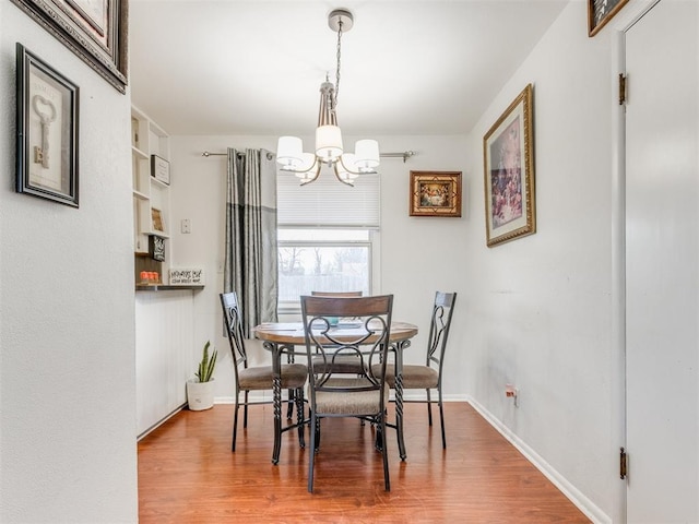 dining room featuring baseboards, wood finished floors, and an inviting chandelier