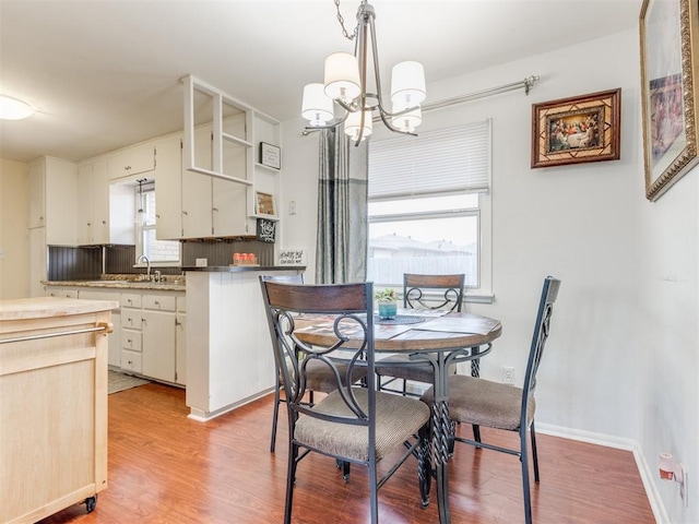 dining room featuring baseboards, an inviting chandelier, and light wood-style floors