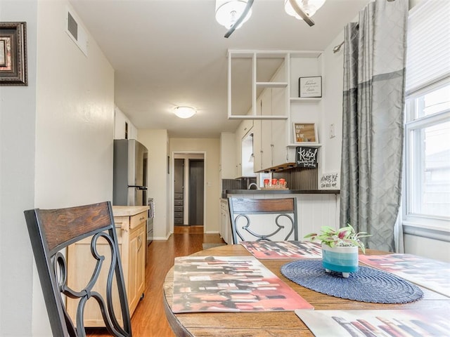 dining room featuring light wood-type flooring, visible vents, and arched walkways