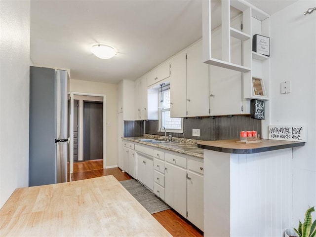 kitchen with freestanding refrigerator, light wood-style floors, white cabinetry, open shelves, and a sink