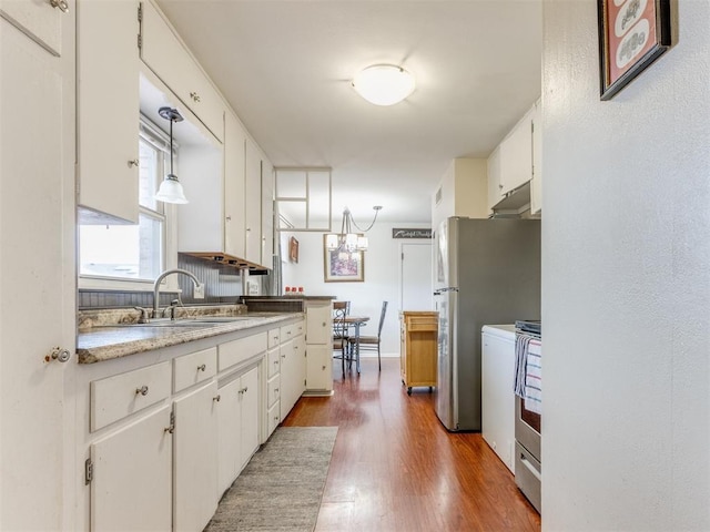 kitchen featuring wood finished floors, freestanding refrigerator, light countertops, white cabinetry, and a sink