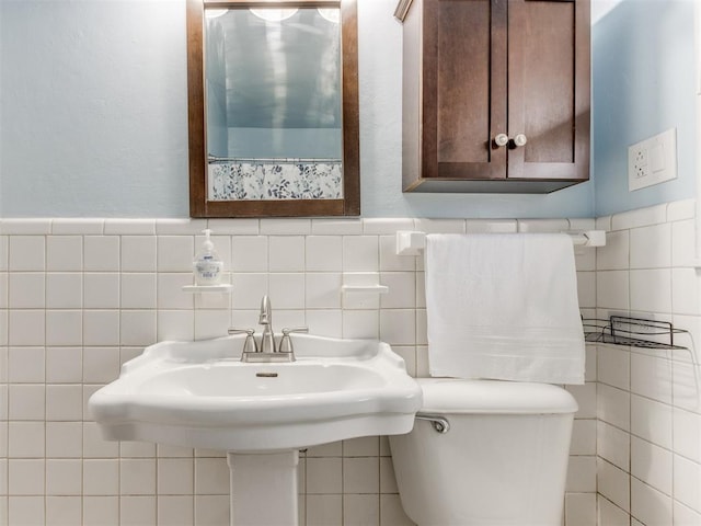 half bath with toilet and tile walls