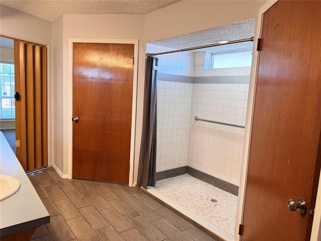 bathroom with a textured ceiling, a stall shower, vanity, and wood tiled floor