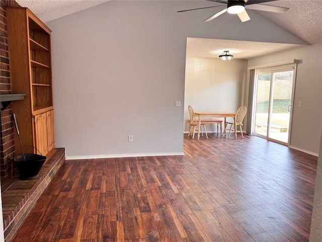 unfurnished living room featuring a textured ceiling, vaulted ceiling, a brick fireplace, and dark wood finished floors