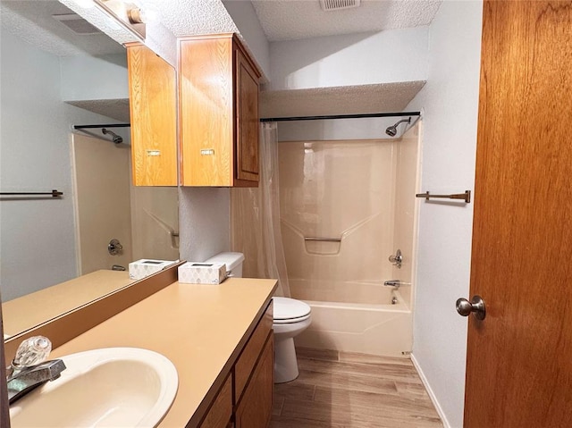 full bath featuring visible vents, wood finished floors, shower / bath combo with shower curtain, a textured ceiling, and vanity