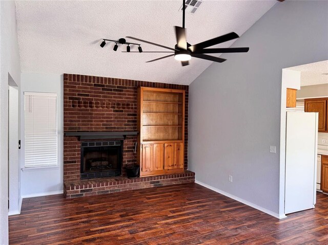 unfurnished living room featuring dark wood finished floors, visible vents, a brick fireplace, vaulted ceiling, and a textured ceiling