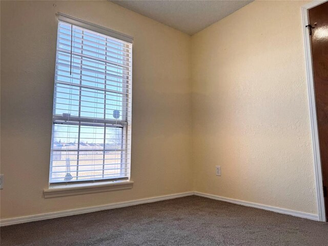 carpeted empty room featuring baseboards