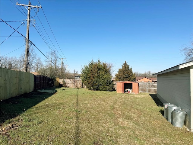 view of yard featuring an outbuilding, a fenced backyard, and a shed