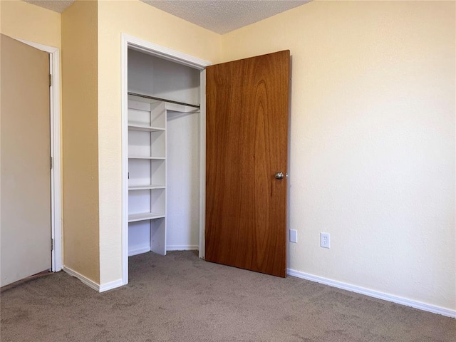 unfurnished bedroom with carpet floors, a closet, baseboards, and a textured ceiling