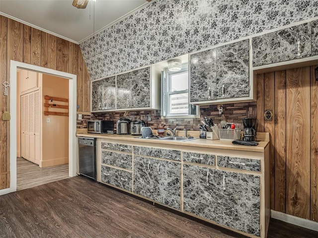 kitchen featuring dark wood finished floors, light countertops, ornamental molding, wooden walls, and dishwasher