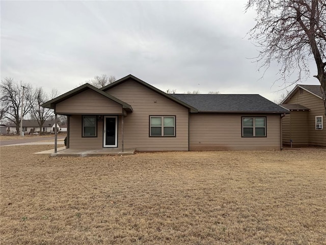 view of front of home featuring roof with shingles and a front yard