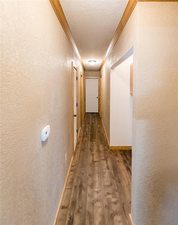 hallway featuring crown molding, a textured wall, and wood finished floors