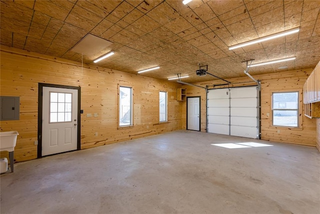 garage featuring wood walls, electric panel, and a garage door opener