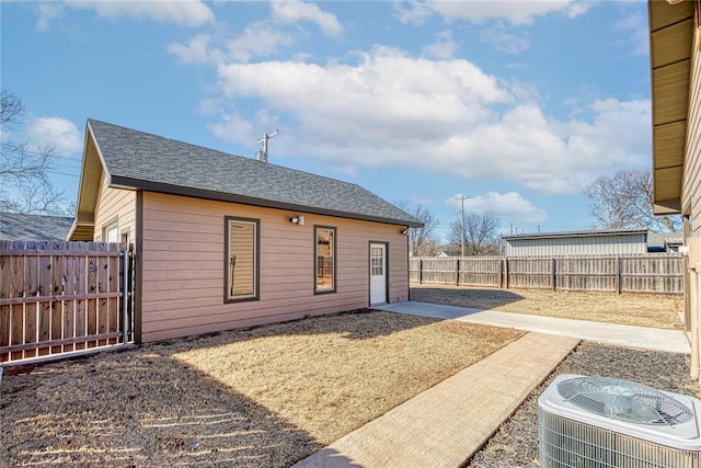 back of property with a patio area, a fenced backyard, cooling unit, and roof with shingles