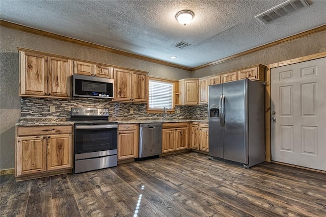 kitchen featuring stainless steel appliances, visible vents, a textured wall, and dark wood-type flooring