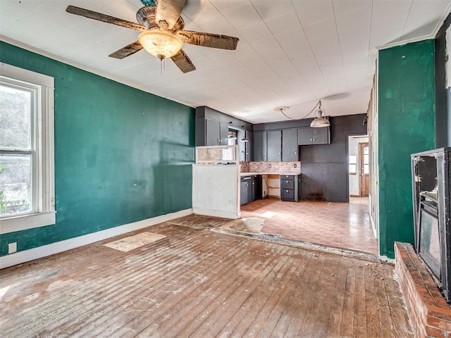 kitchen featuring gray cabinetry, a ceiling fan, baseboards, light wood finished floors, and tasteful backsplash