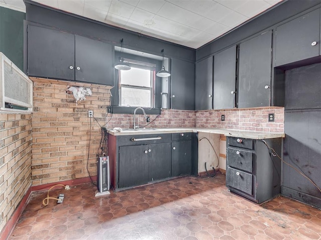 kitchen with brick wall, cooling unit, light countertops, and a sink