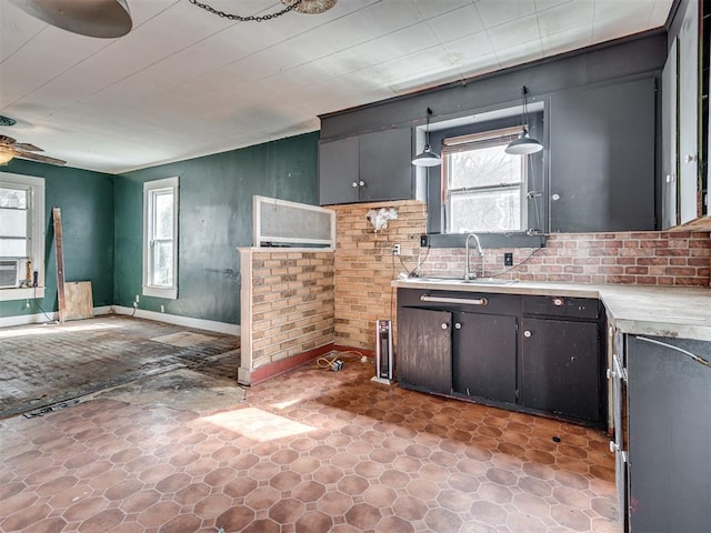 kitchen featuring ceiling fan, light countertops, a sink, and baseboards