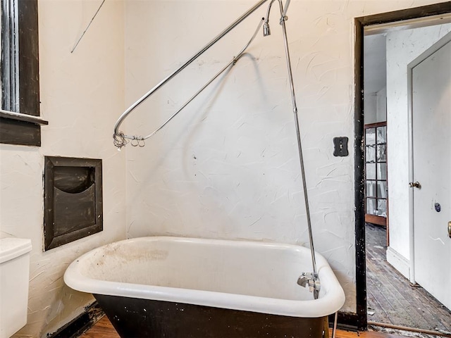 bathroom with a soaking tub and toilet