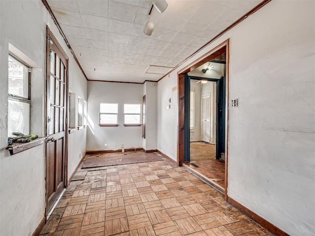 empty room featuring track lighting, baseboards, and crown molding