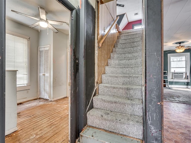 staircase with a ceiling fan, cooling unit, baseboards, and hardwood / wood-style flooring