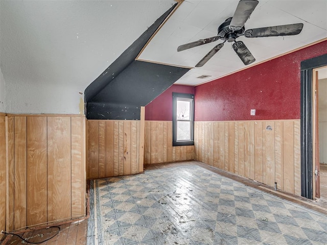 additional living space featuring visible vents, a ceiling fan, wainscoting, tile patterned floors, and wood walls