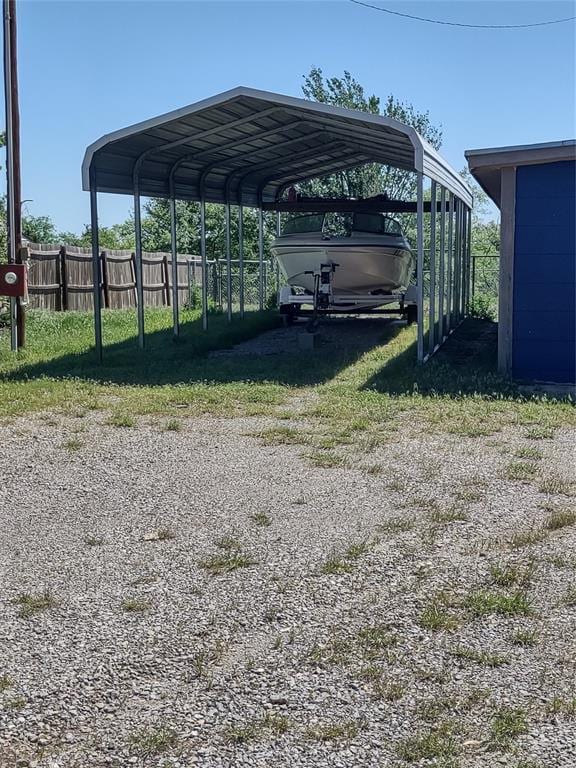 view of vehicle parking featuring fence, a carport, and driveway