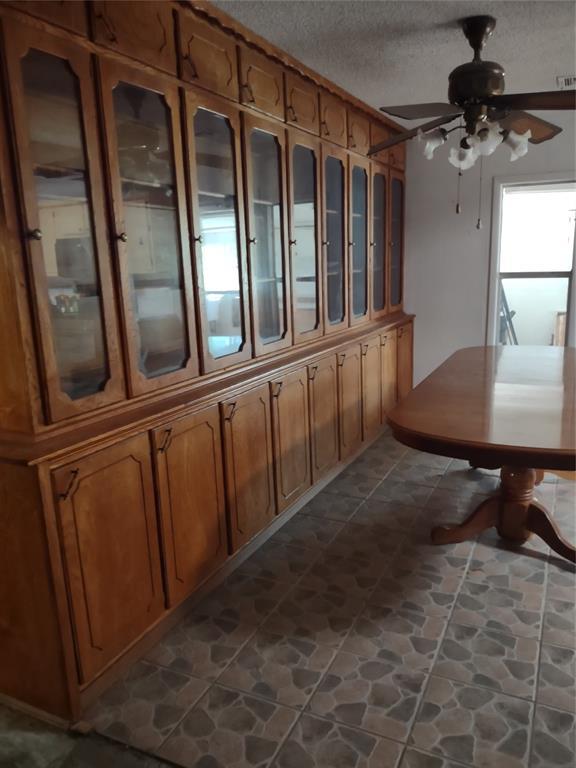 unfurnished dining area featuring stone finish floor, a textured ceiling, and ceiling fan