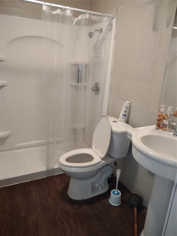full bath with toilet, wood finished floors, a sink, and a stall shower
