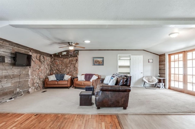 carpeted living area with vaulted ceiling, french doors, and a textured ceiling