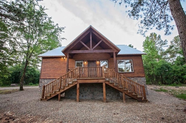 back of house featuring faux log siding, metal roof, and stairway