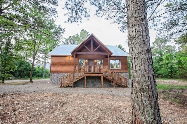 rear view of house featuring faux log siding, metal roof, and stairway