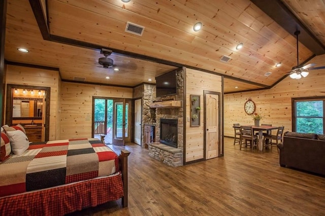 bedroom featuring wood ceiling, wooden walls, wood finished floors, and a stone fireplace