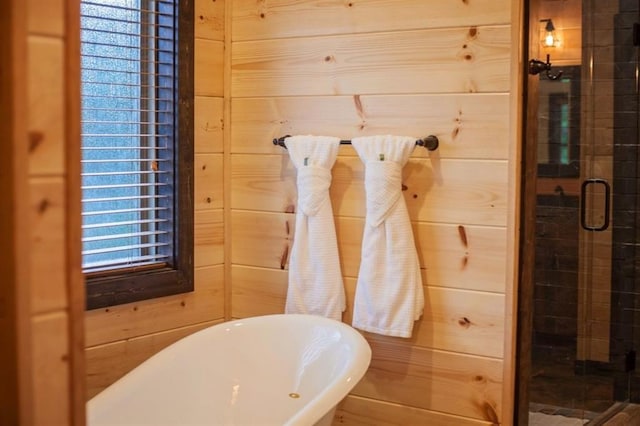 full bathroom featuring a freestanding tub, a shower stall, and wooden walls