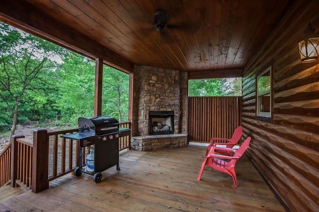 wooden deck with an outdoor stone fireplace and grilling area