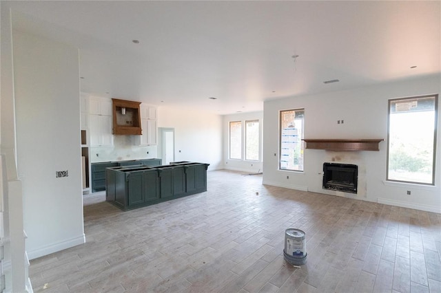 kitchen with a fireplace, light wood-style flooring, a center island, and open floor plan