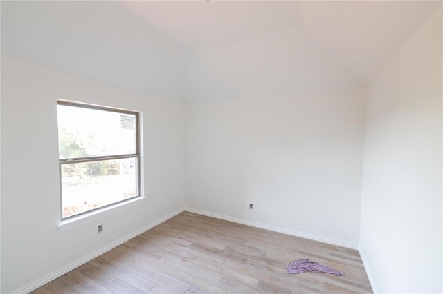 unfurnished room featuring light wood-style floors, vaulted ceiling, and baseboards