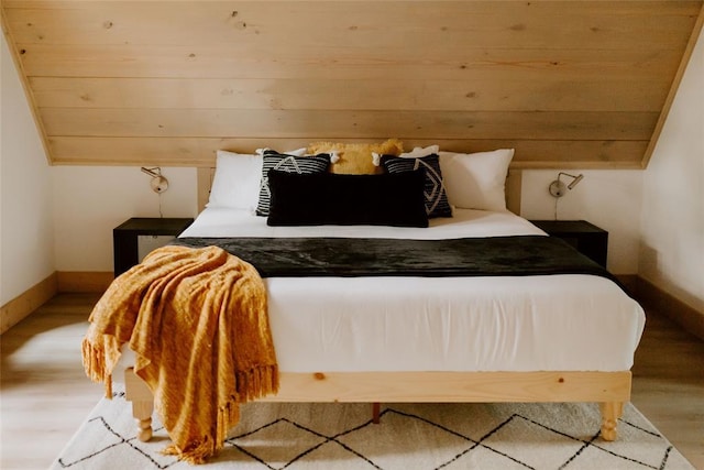 bedroom featuring baseboards, vaulted ceiling, and wood finished floors