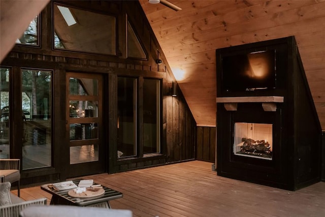 interior space featuring vaulted ceiling, a multi sided fireplace, hardwood / wood-style flooring, and wooden walls