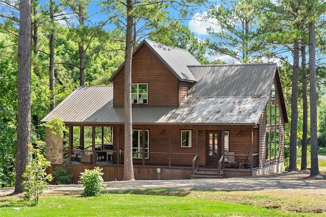 back of house with metal roof, a porch, a lawn, and log veneer siding