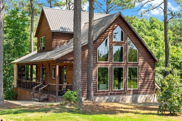 view of home's exterior with covered porch, log veneer siding, and metal roof